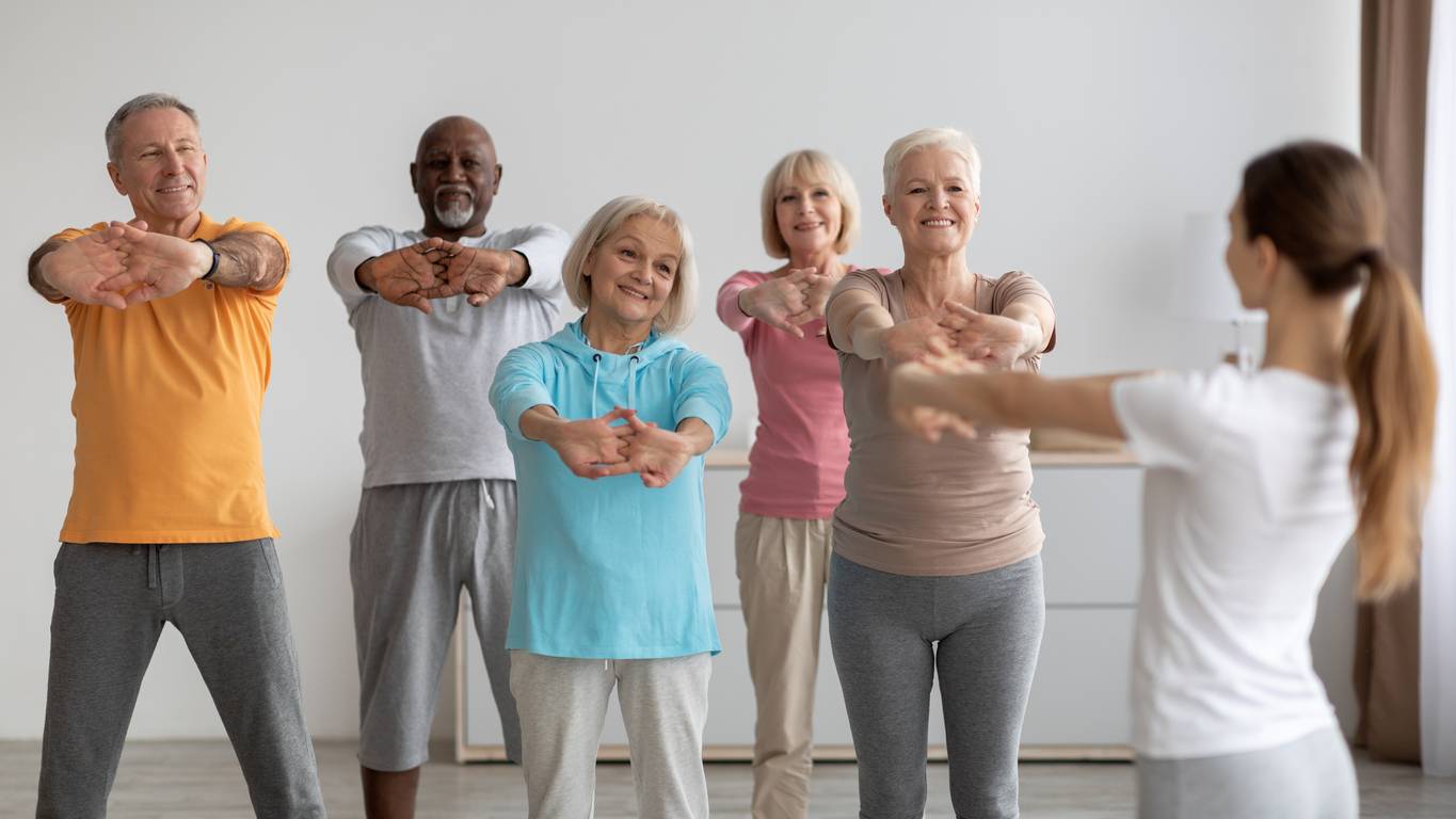 Elderly people stretching their arms in a group cool-down 
