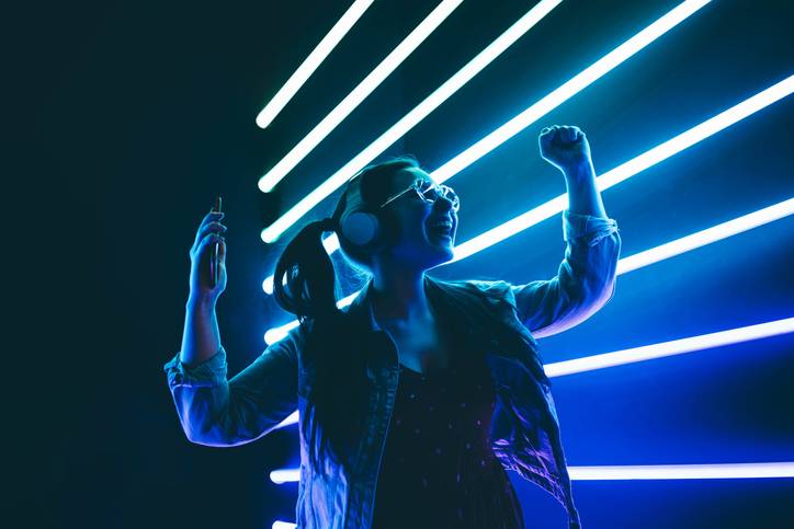 woman dances alone at a silent disco in front of neon lights