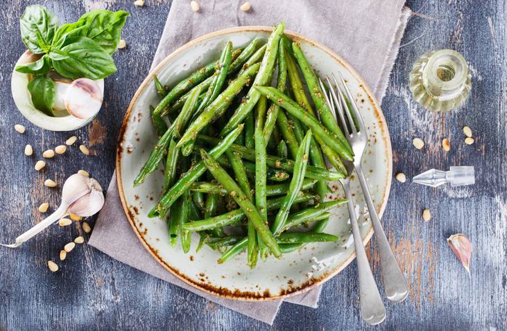 cooked green beans in a bowl with herbs on top