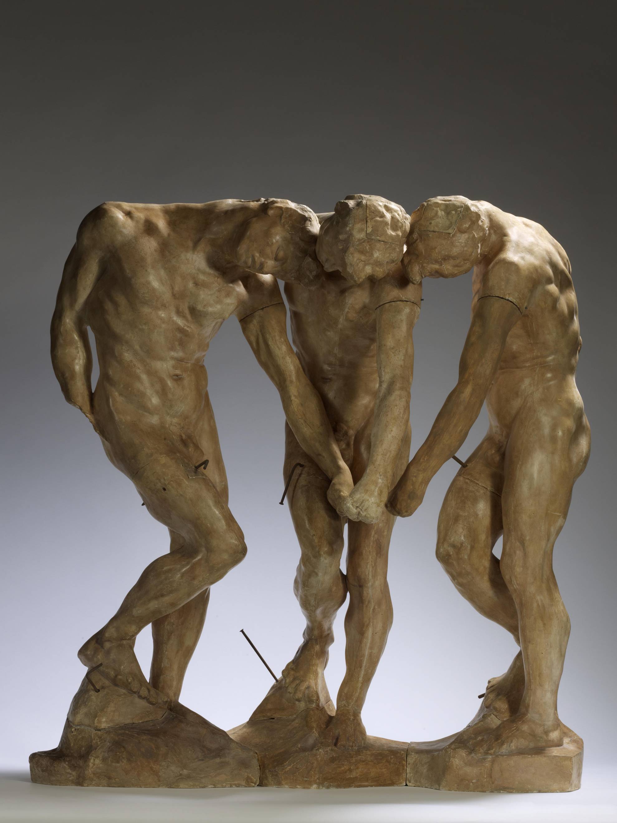 Auguste Rodin's The Three Shadows scultpture, three men join hands and bend slightly inwards towards each other