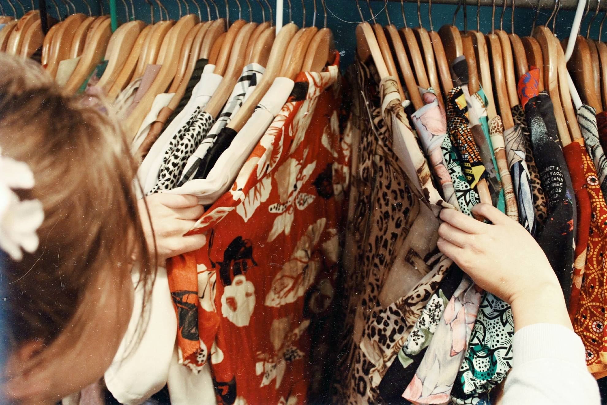 woman's arm rifling through vintage clothing on a rack