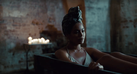 Beyonce alone in a bath tub with candles