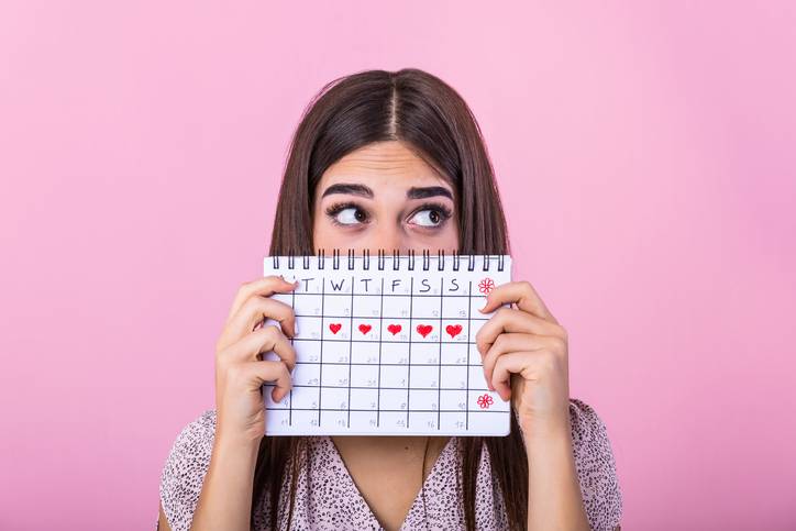 girl holds a calendar marked with the days of her period