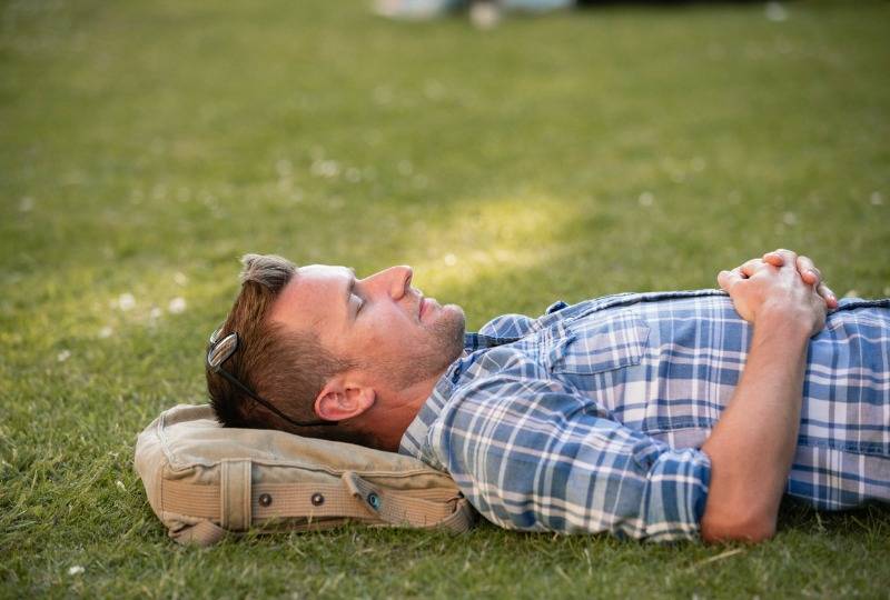 A man lies on the ground with hands on his stomach