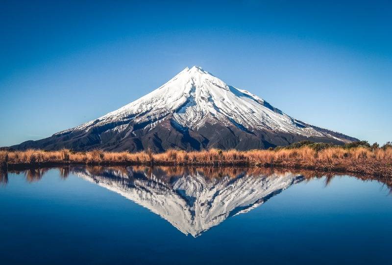 Snow-topped Mount Taranaki and its reflection in the water in front, New Zealand