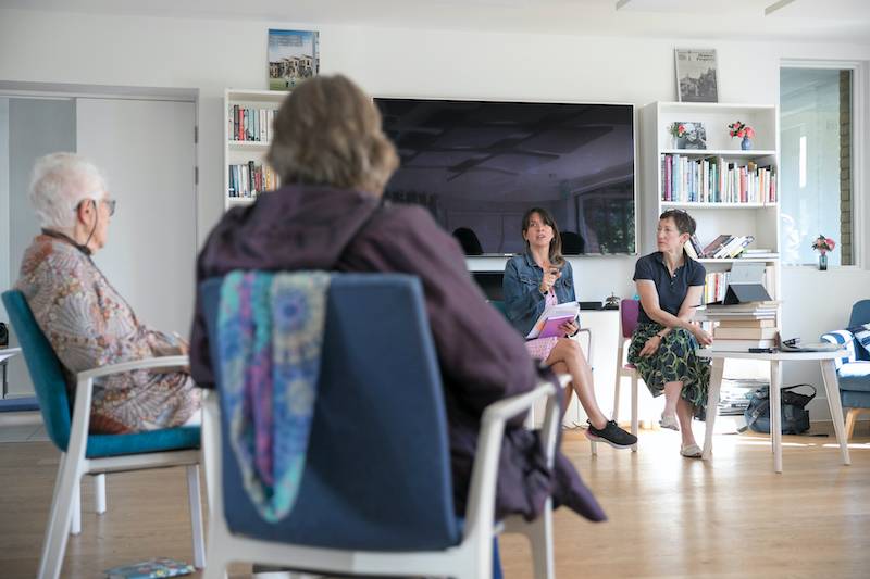 New Ground cohousing residents sit on chairs talking to researchers