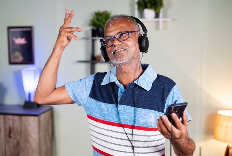 Old man wears headphones and sings in living room