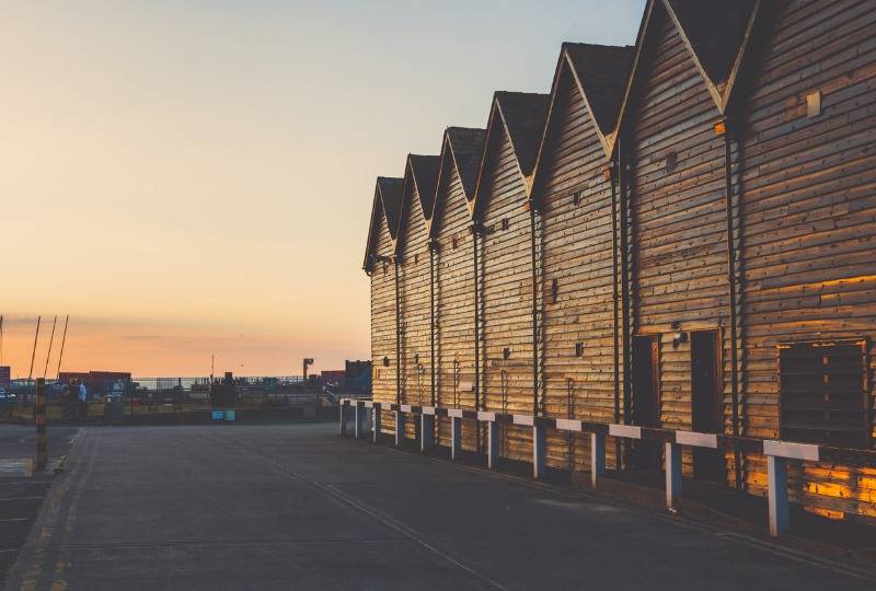 Whitstable fishermen's huts on coast lit by sunset