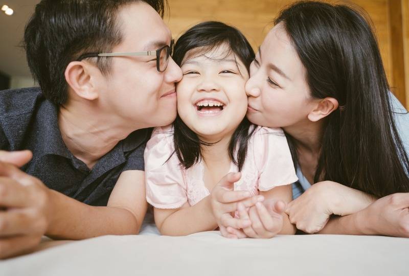 Two Chinese parents cuddle only child