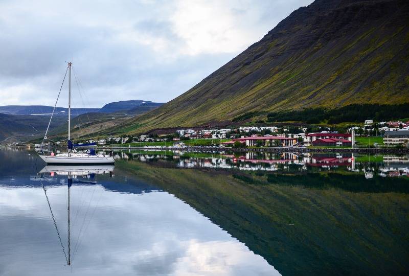 Boat sits on water near Ísafjörður port with view of hills behind in Iceland
