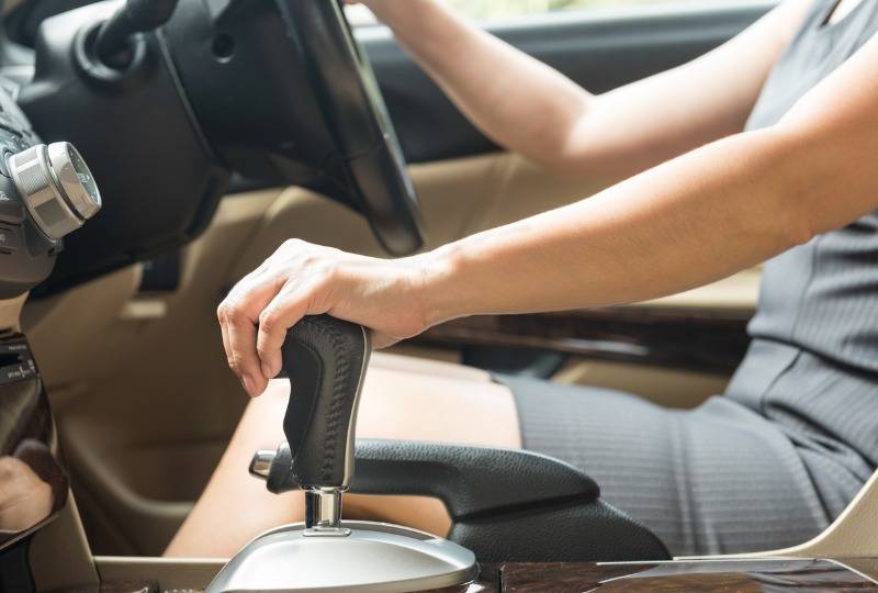 Woman rests hand on gearstick in manual car