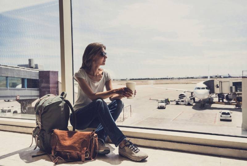 Woman stuck at airport drinking takeaway coffee