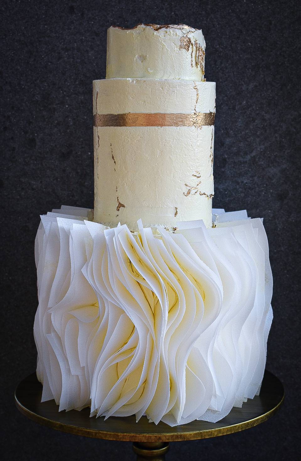 Three tier white wedding cake with gold leaf decor