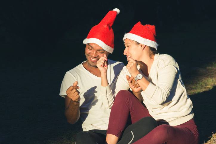 a couple share a carolling date in matching Santa hats