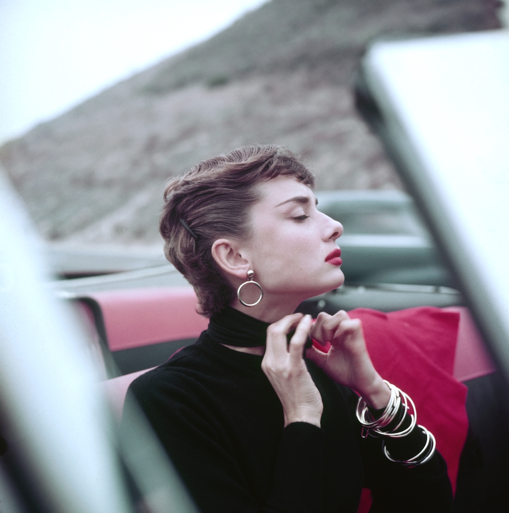 Audrey Hepburn adjusting scarf in car