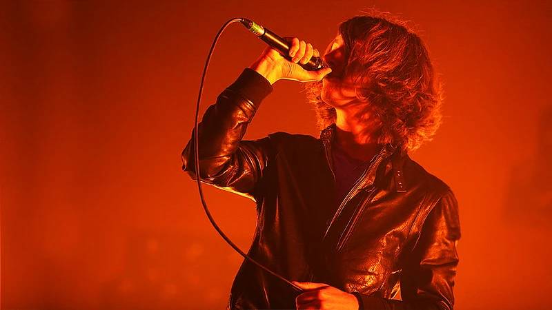 Arctic Monkeys' Alex Turner singing on a red-lit stage