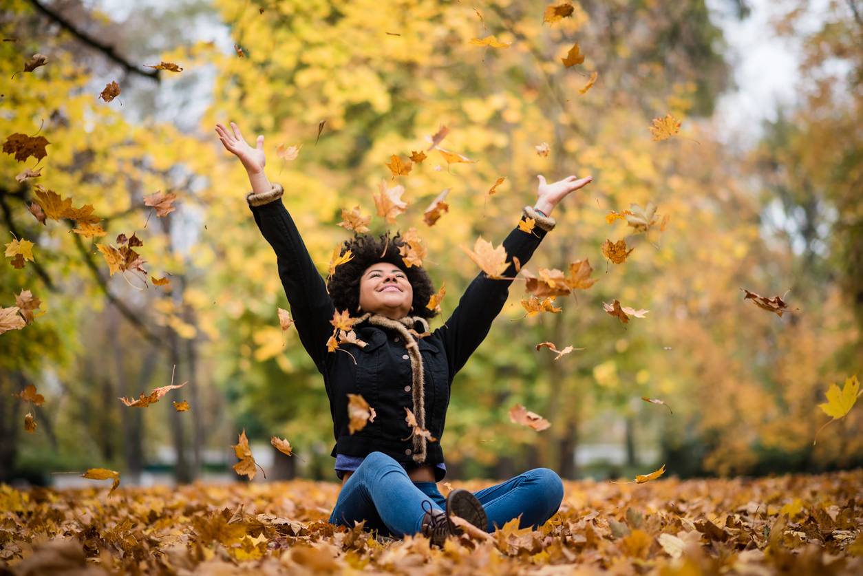 A girl throwing autumn leaves in the air