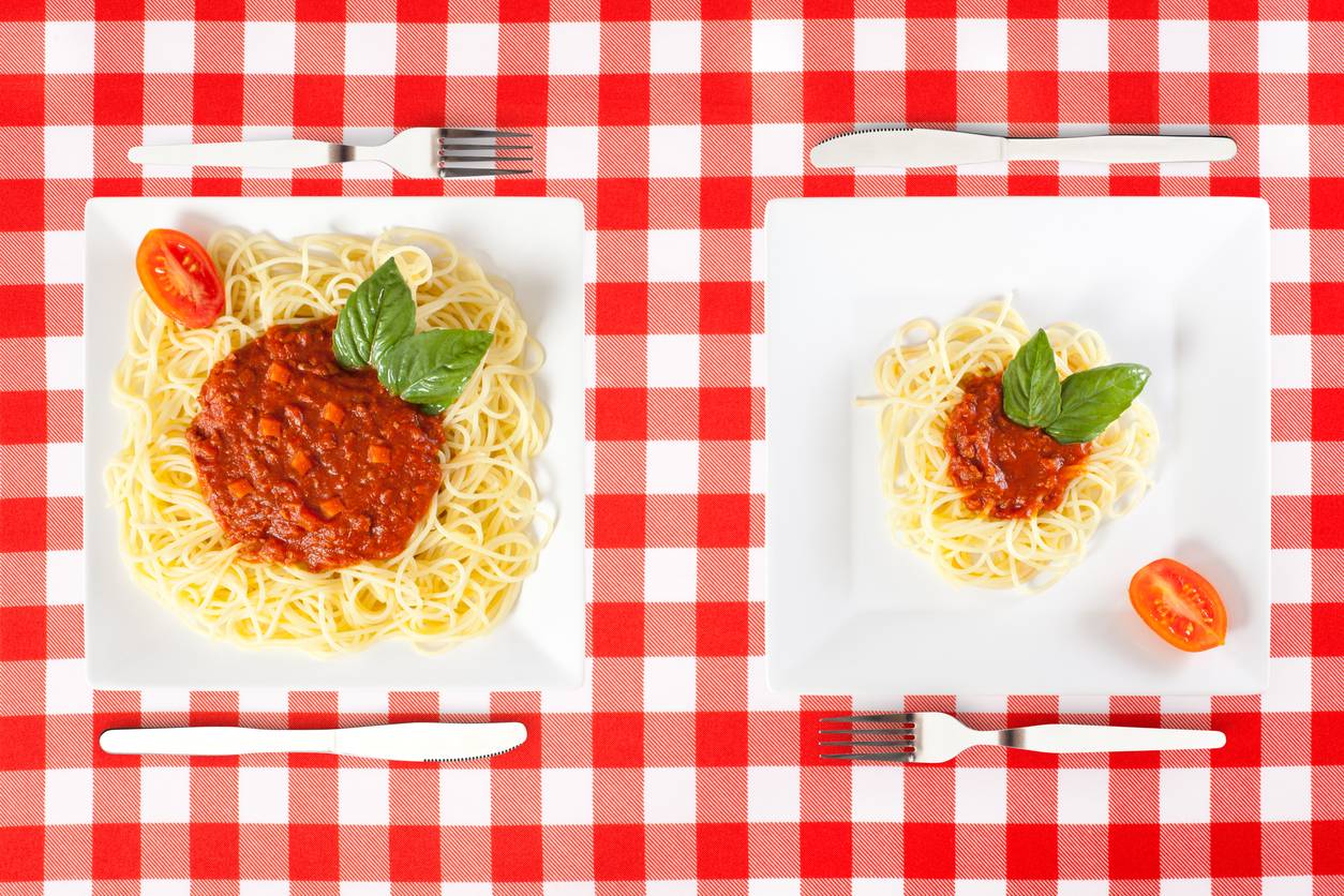 Large and small portion plates of spaghetti bolognese