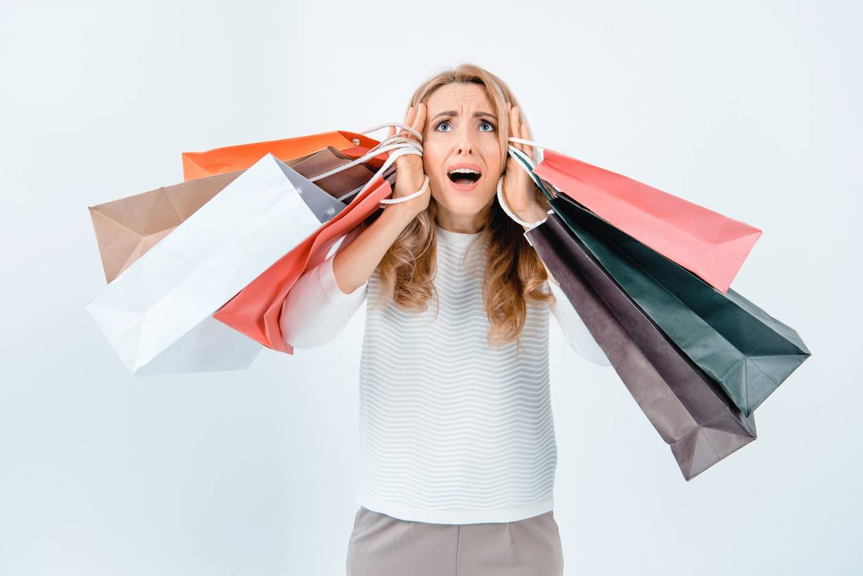 A woman with a scared expression holding shopping bags