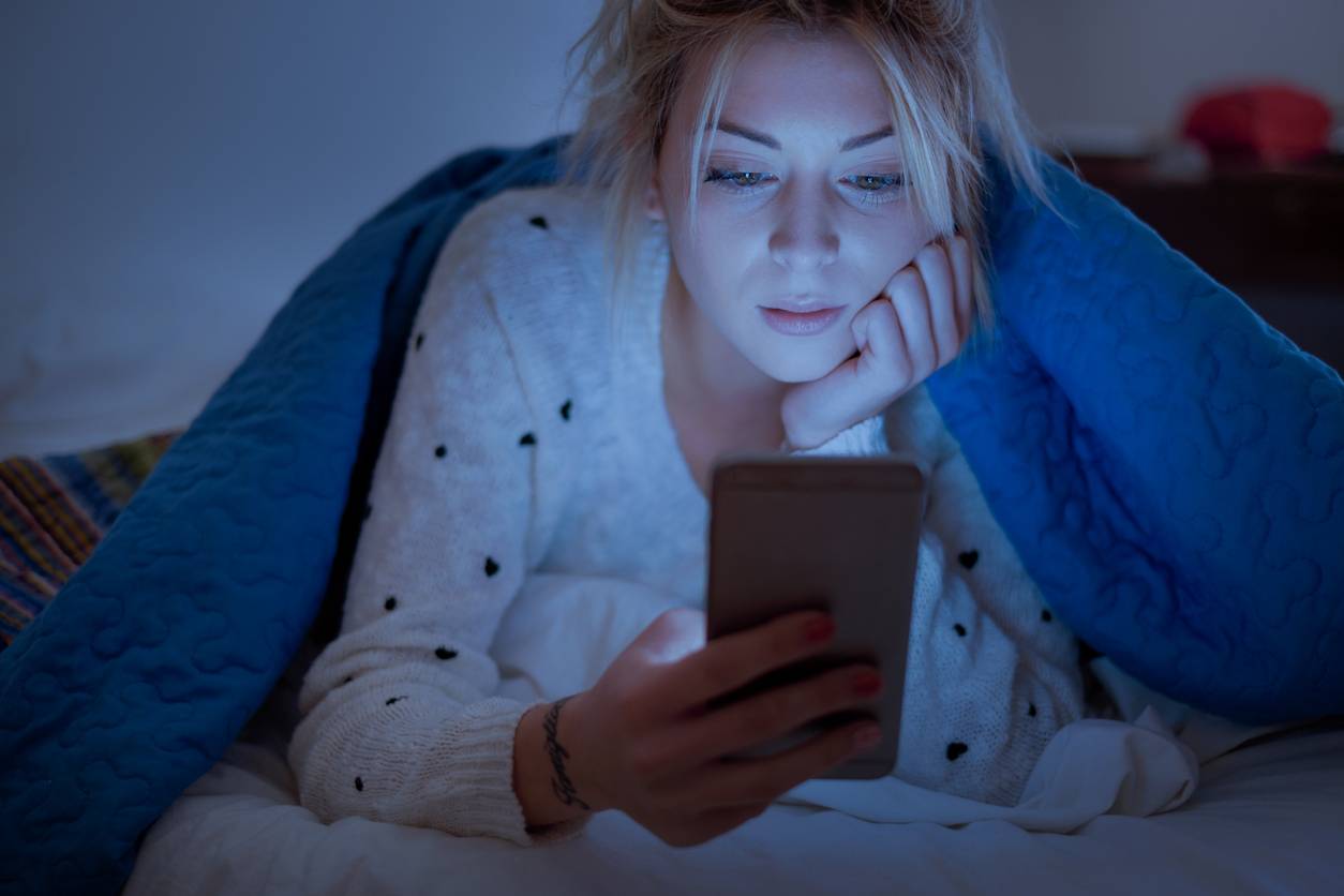 A woman staring at her phone in bed