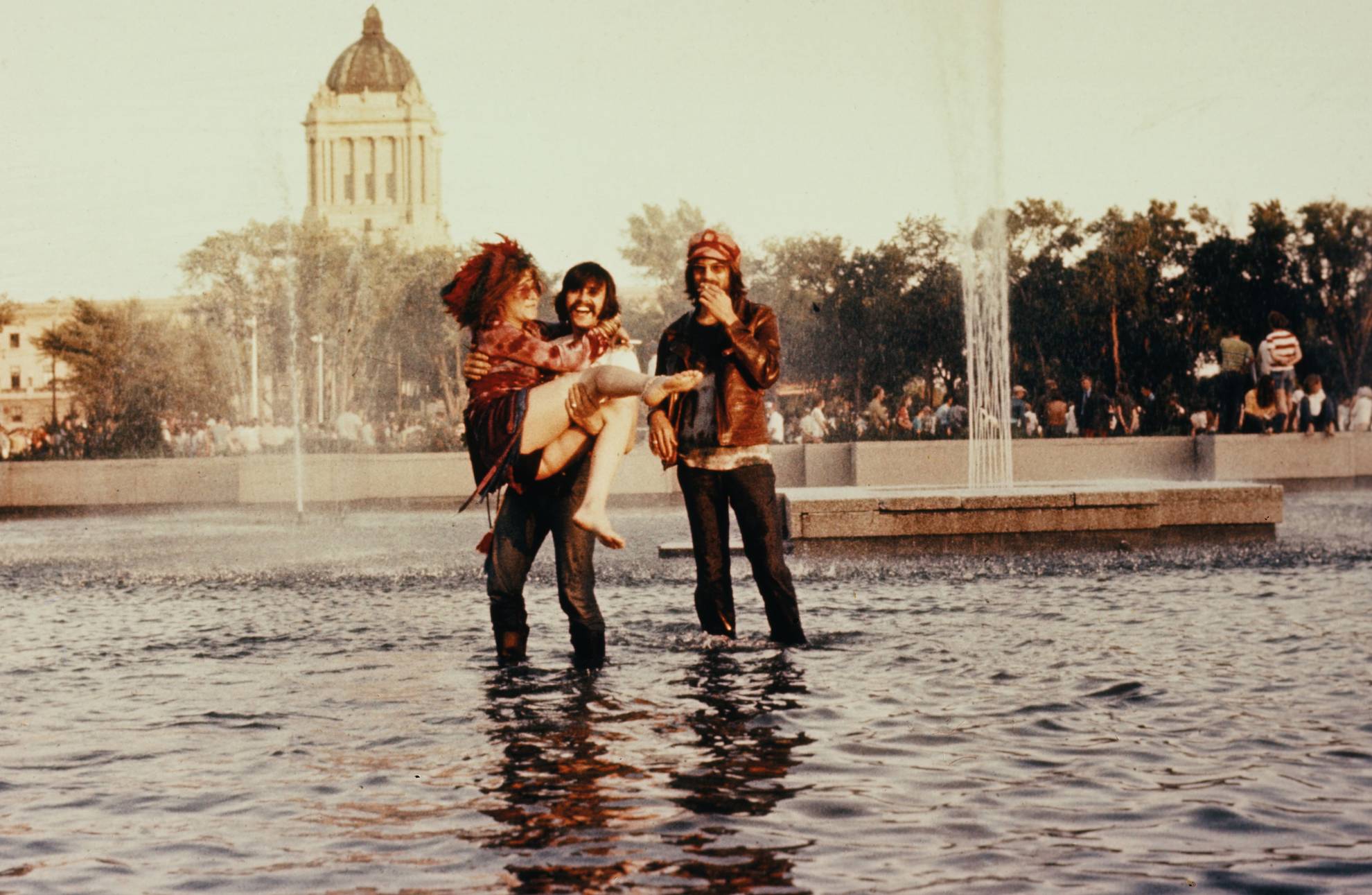 Janis Joplin being carried by a friend in a water fountain in 1970