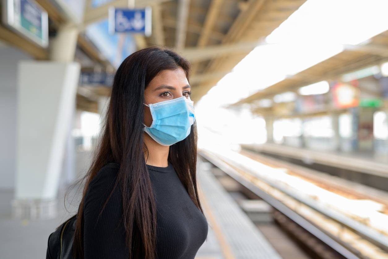 Young woman wearing a mask at a train station