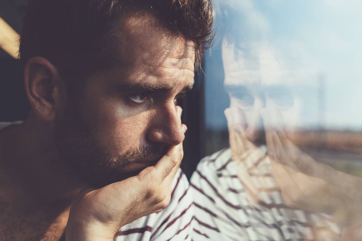 Worried white man looking out of window