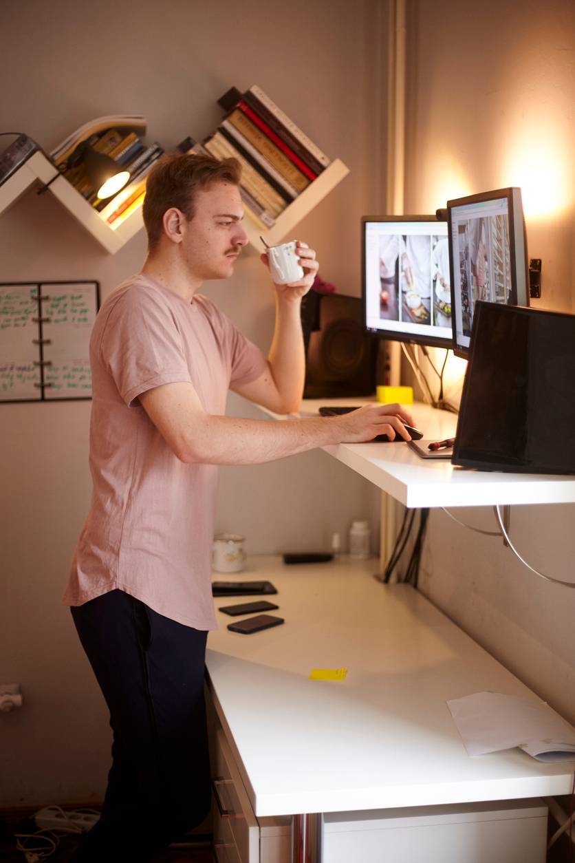 Man standing using a standing desk at home